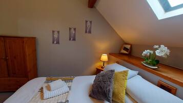 A bedroom with a bed, a nightstand, a lamp, a wooden dresser, and wall-mounted decorations.