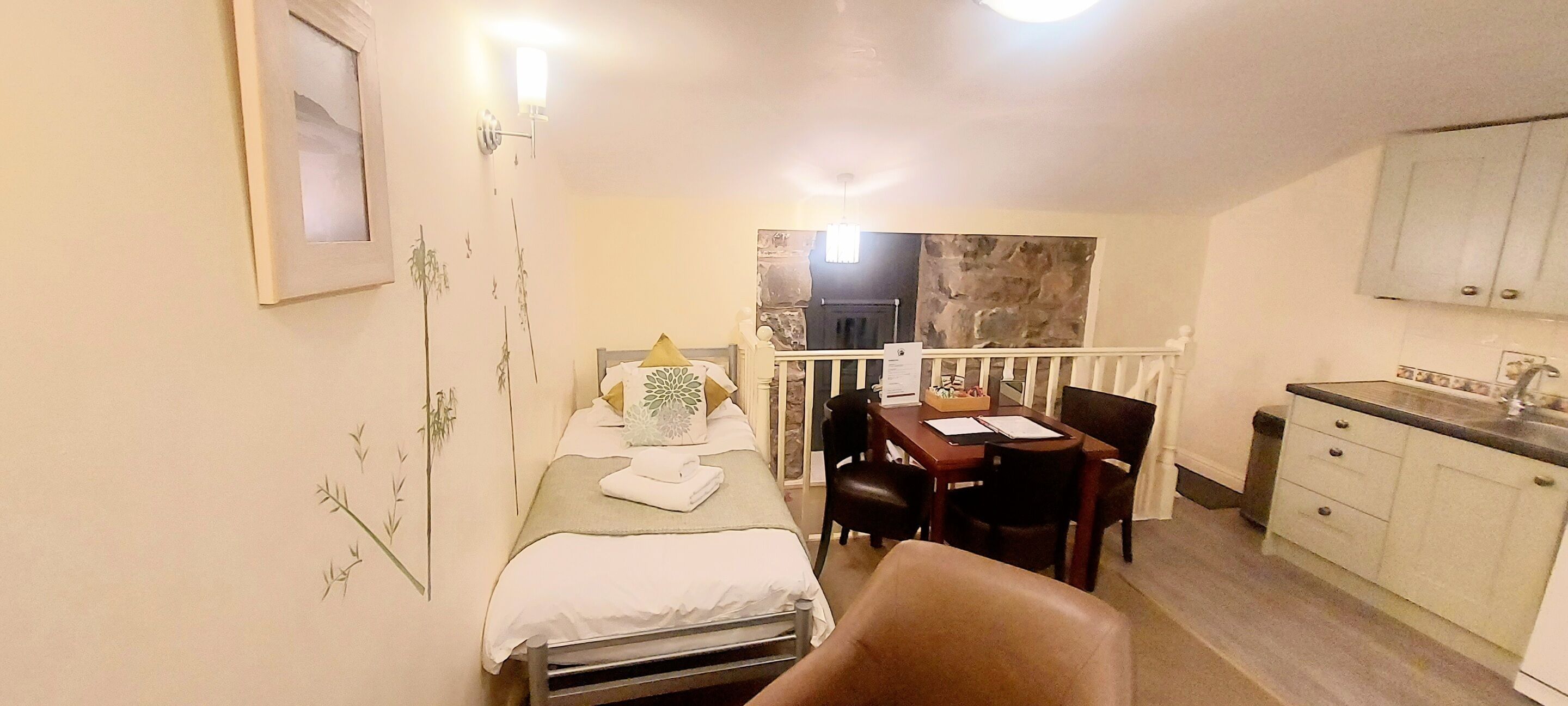 A compact room with a bed, a small table with chairs, a kitchenette, and a bathroom with a shower.