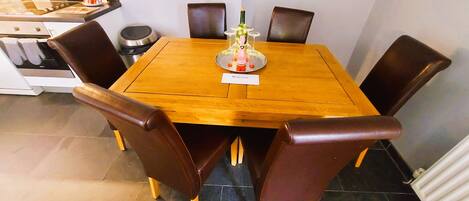 A dining table with six chairs, a bottle of wine, and a 'Welcome' sign.