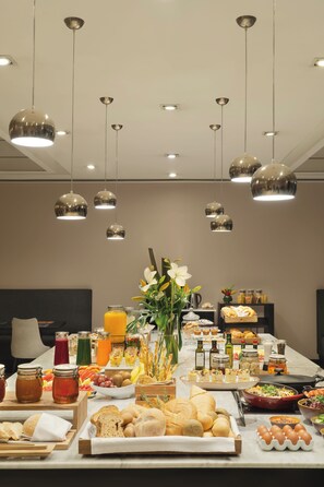 A breakfast buffet with various food items and a vase of flowers. - NH Buenos Aires Tango (Buenos Aires)
