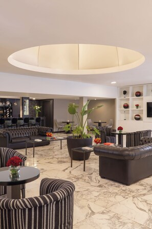 A spacious lounge area with leather sofas, a large central table, and a modern ceiling light fixture. - NH Buenos Aires Tango (Buenos Aires)