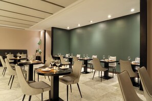 A restaurant with multiple tables and chairs, marble flooring, and recessed ceiling lighting. - NH Buenos Aires Tango (Buenos Aires)