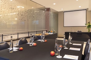 A conference room with a glass partition, a projector screen, and a buffet table with fruits and beverages. - NH Buenos Aires Tango (Buenos Aires)