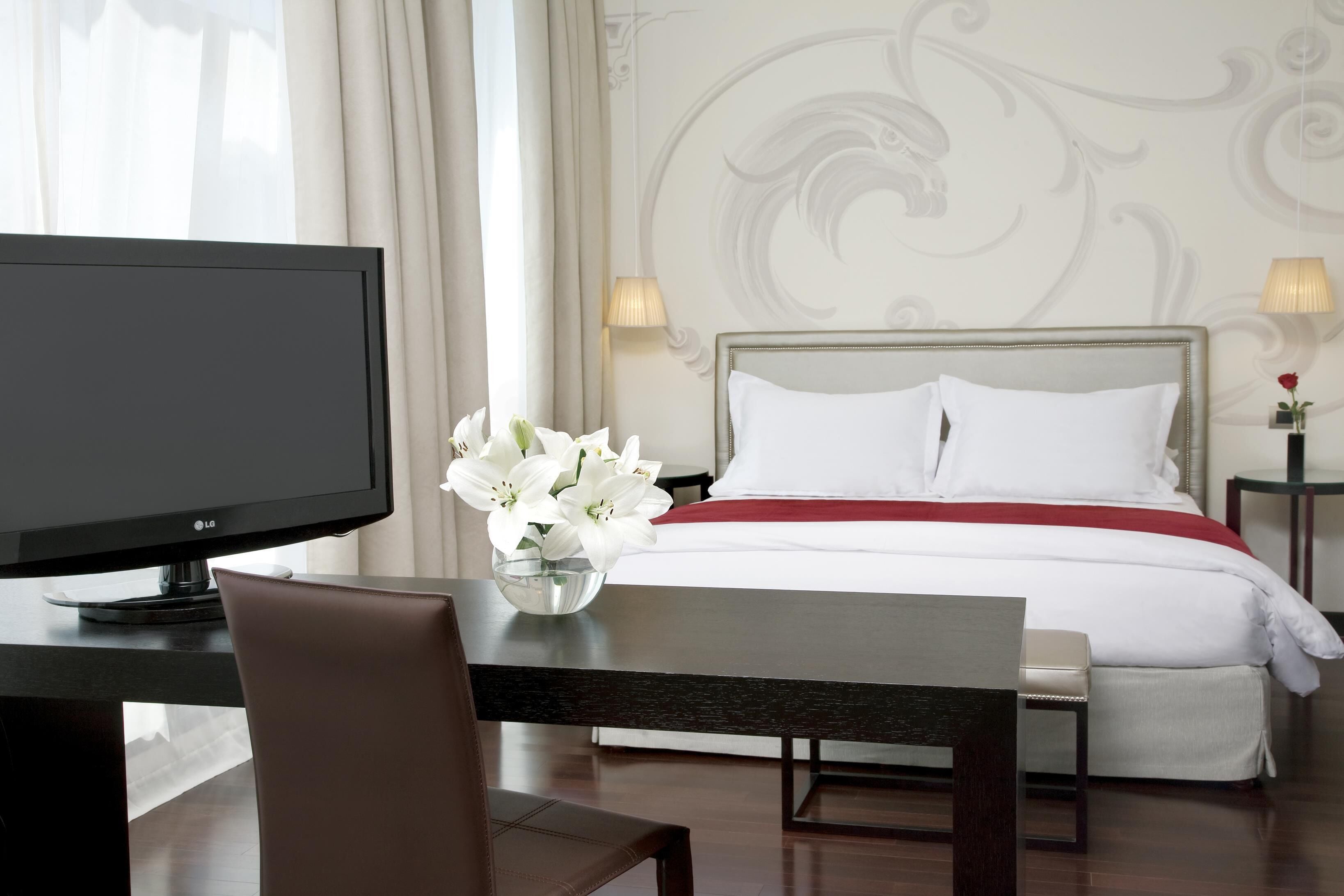 A hotel room with a bed, a TV, a desk, and a chair.