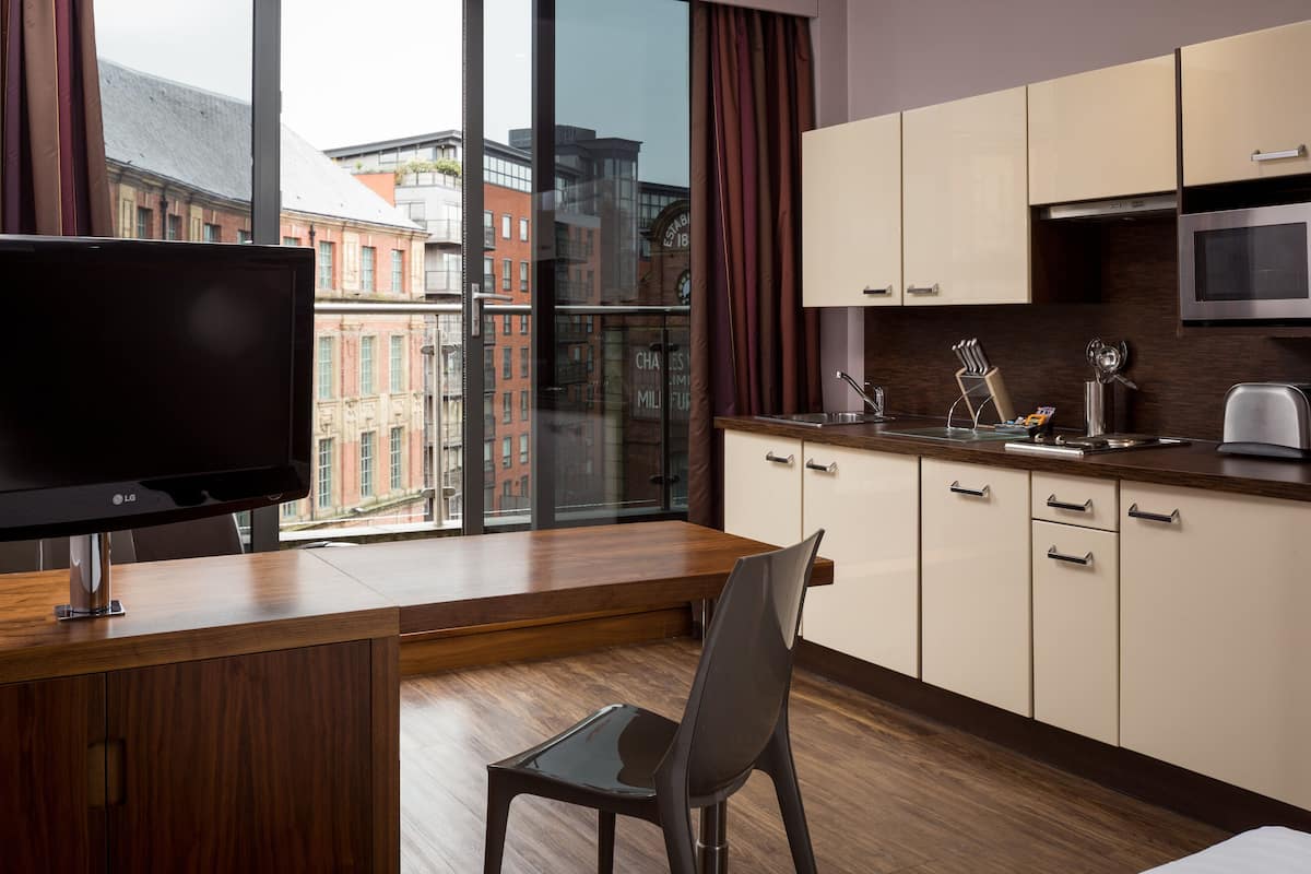 A modern kitchen with a large window, a flat-screen TV, and a dining area with a chair.