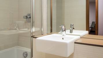 A modern bathroom with a glass-enclosed shower, two sinks, and a large mirror.