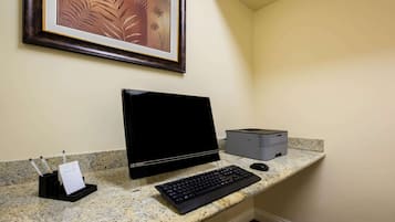 Una computadora de escritorio con monitor, teclado e impresora sobre una encimera de granito.