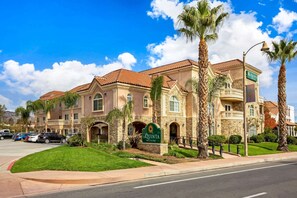 A hotel with a stone facade, multiple balconies, and palm trees.