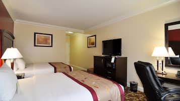 Habitación de hotel con dos camas, televisor, escritorio con lámpara y una silla.