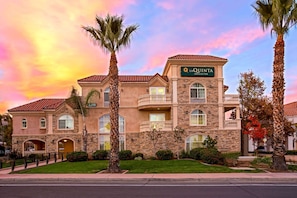 A large, two-story hotel with a stone facade, multiple balconies, and a sign reading "LA QUINTA INN & SUITES."