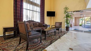 A lobby with a sofa, armchairs, a television, and a large window with curtains. - La Quinta Inn & Suites by Wyndham Moreno Valley (Moreno Valley)