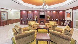 A modern living room with a fireplace, two armchairs, a coffee table, and a TV. - La Quinta Inn & Suites by Wyndham Columbus TX (Columbus)
