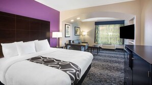 A hotel room with a large bed, a desk, a TV, and a seating area. - La Quinta Inn & Suites by Wyndham Columbus TX (Columbus)