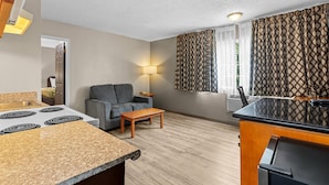 A compact living space with a kitchenette, a sofa, a dining table, and a patterned curtain. - Rodeway Inn & Suites Portland West - Beaverton (Portland)