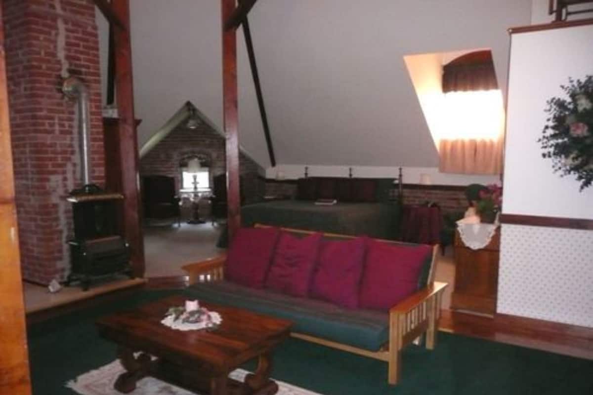 Un salon chaleureux avec un canapé en bois, une table basse et une cheminée en briques.