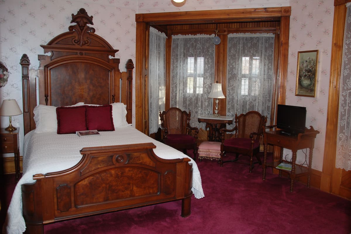 Une chambre à coucher de style traditionnel, avec un lit en bois, une petite table et un téléviseur.