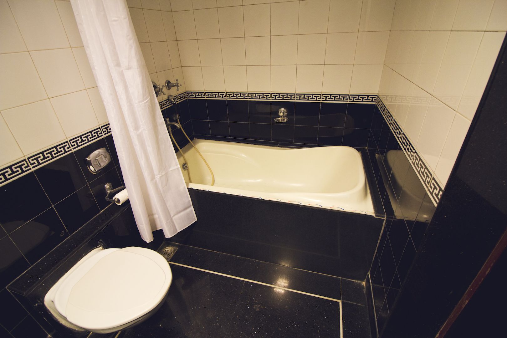 A bathroom with a bathtub, toilet, and a shower curtain.