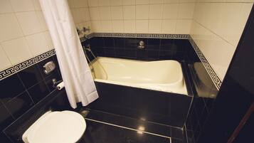 Un baño con bañera, inodoro y cortina de ducha.