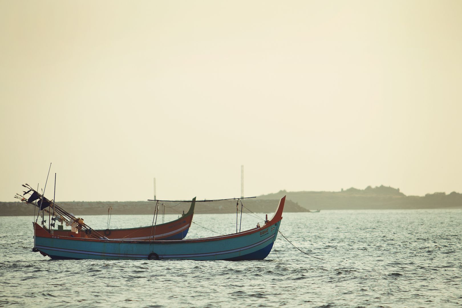 Two traditional boats on calm water with a distant shoreline.
