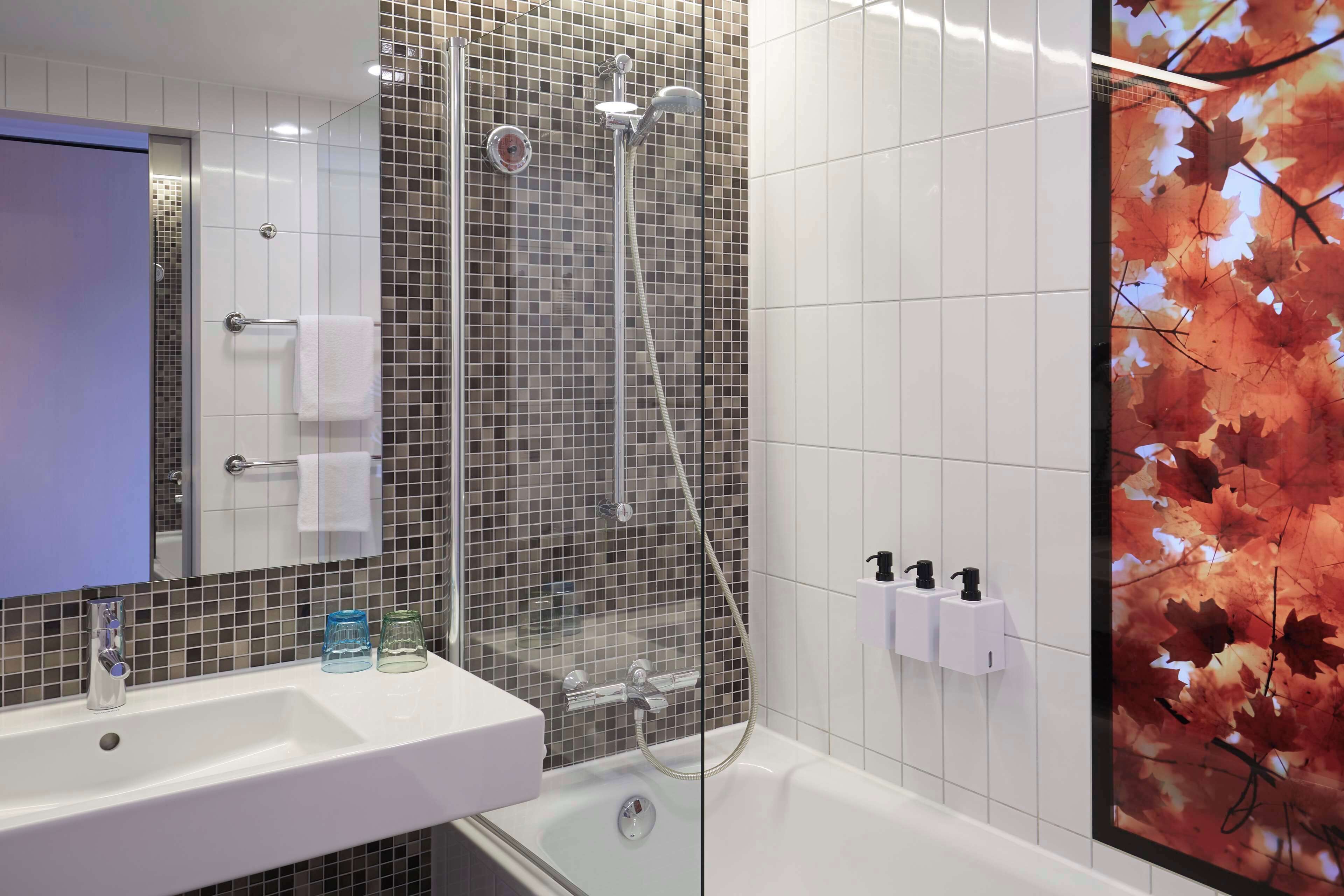 Un baño con ducha, lavamanos y espejo.
