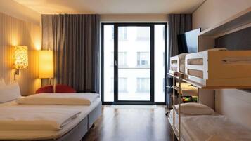 Ein Hotelzimmer mit zwei Betten, einem Fernseher und einem großen Fenster mit Vorhängen.