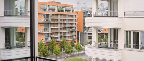 Un immeuble résidentiel à plusieurs étages, doté de balcons, d’une pelouse verdoyante et offrant une vue dégagée sur les environs.