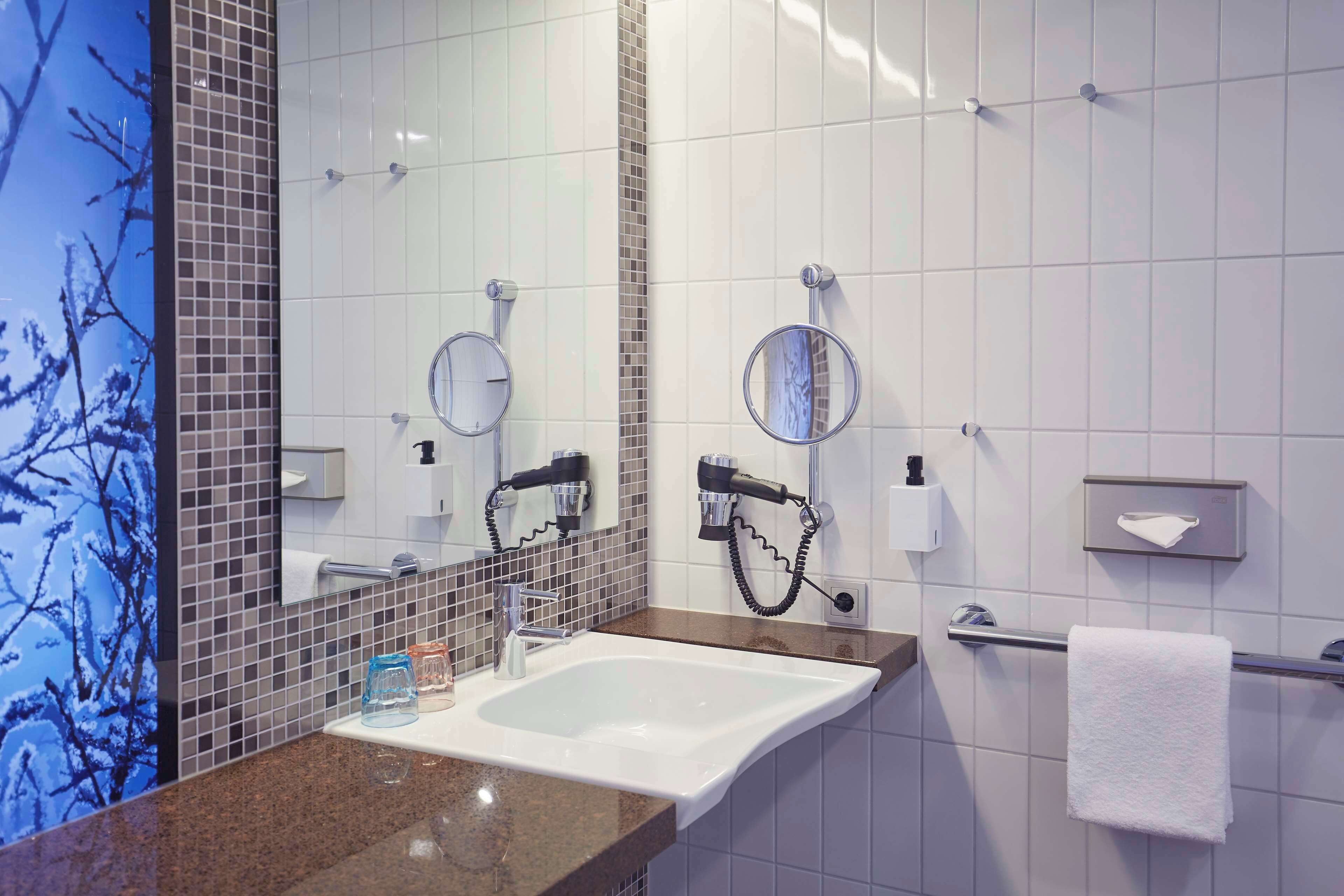 Un bagno moderno con un lavandino grande, due specchi e un porta asciugamani.