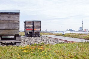 A wooden structure with a metal platform, surrounded by gravel and grass, with a cityscape in the background. - Scandic Berlin Potsdamer Platz (Berlin)