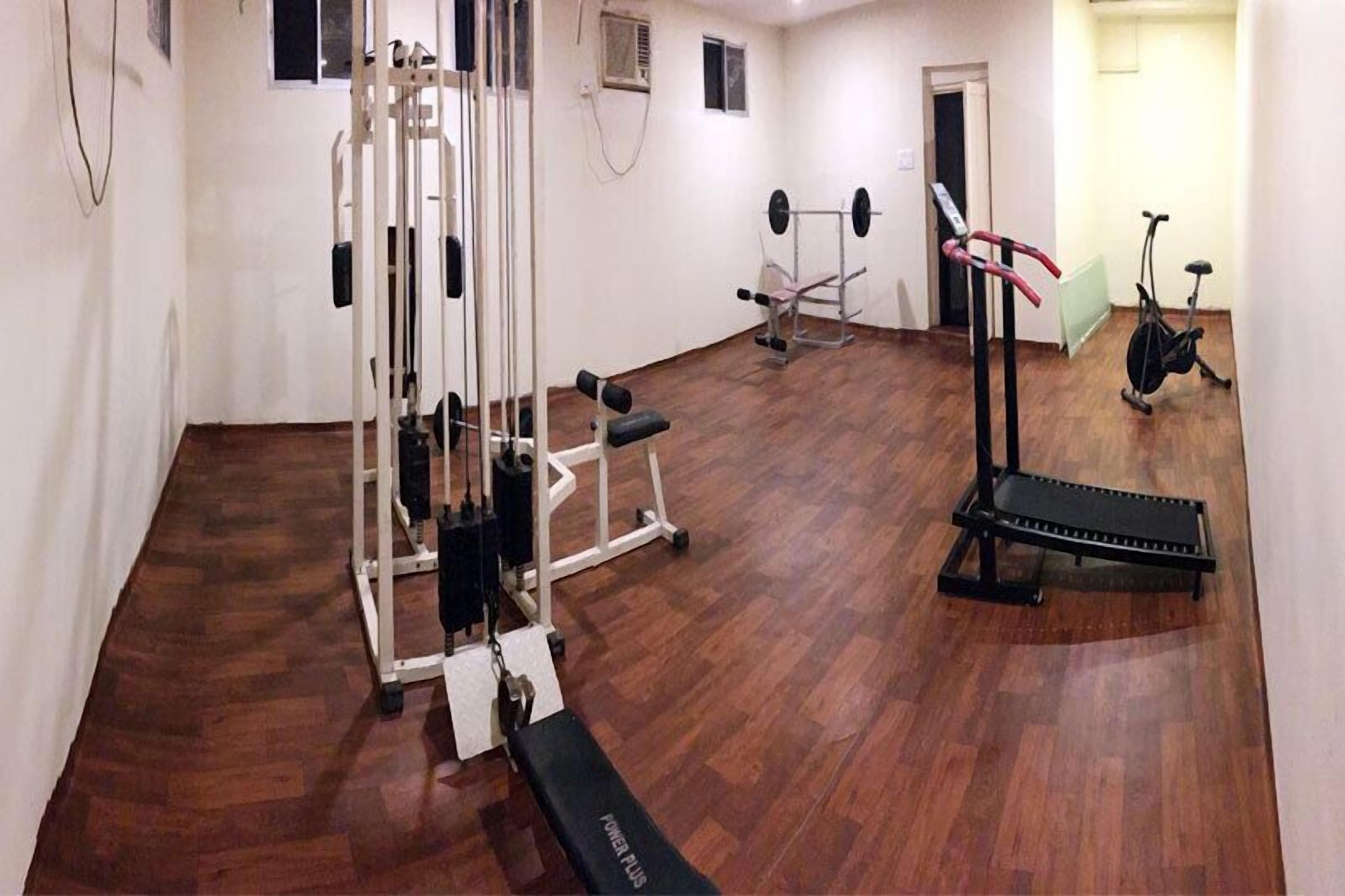 A gym with a variety of equipment including a squat rack, a bench press, and a stationary bike.