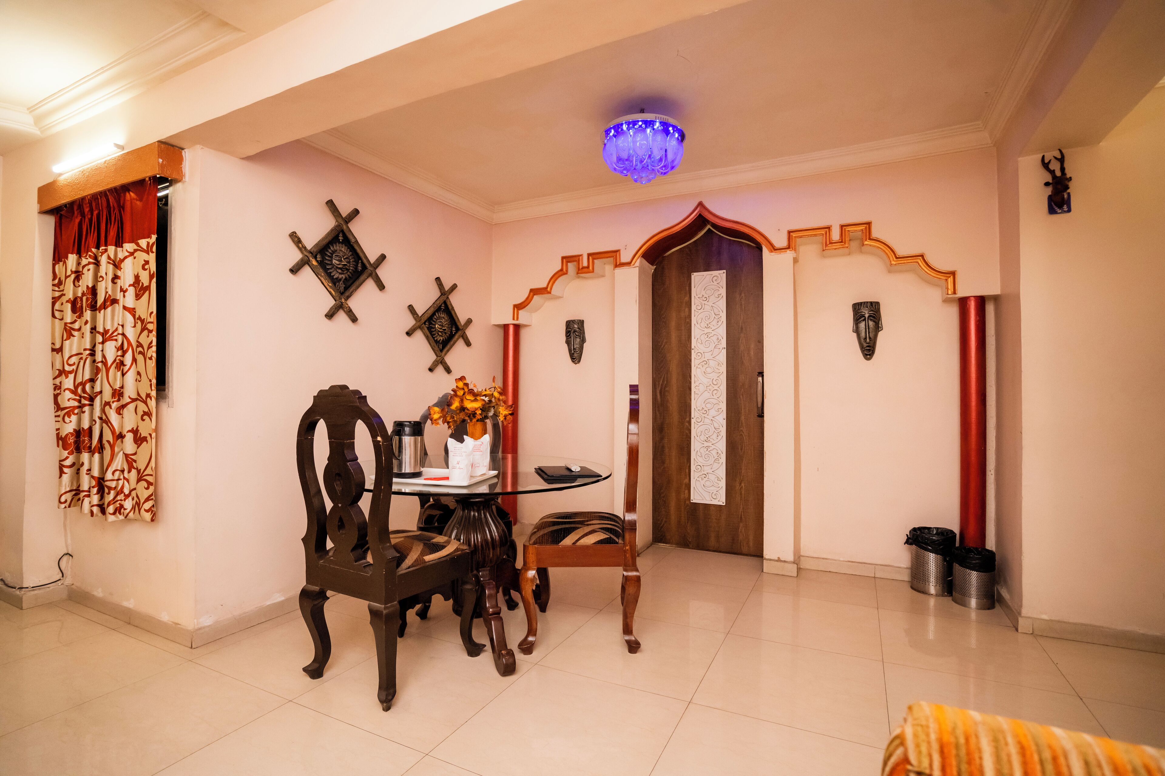 A room with a dining table, chairs, a chandelier, and decorative masks on the walls.