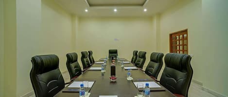 A conference room with a long table, black leather chairs, water bottles, and a whiteboard.