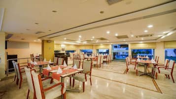 Enjoy meals in this elegant dining area with tables set for a comfortable meal, surrounded by large windows offering a scenic view.