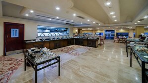 A spacious dining area with multiple tables and a buffet setup. - Royal Sarovar Portico Siliguri (Jalpaiguri)