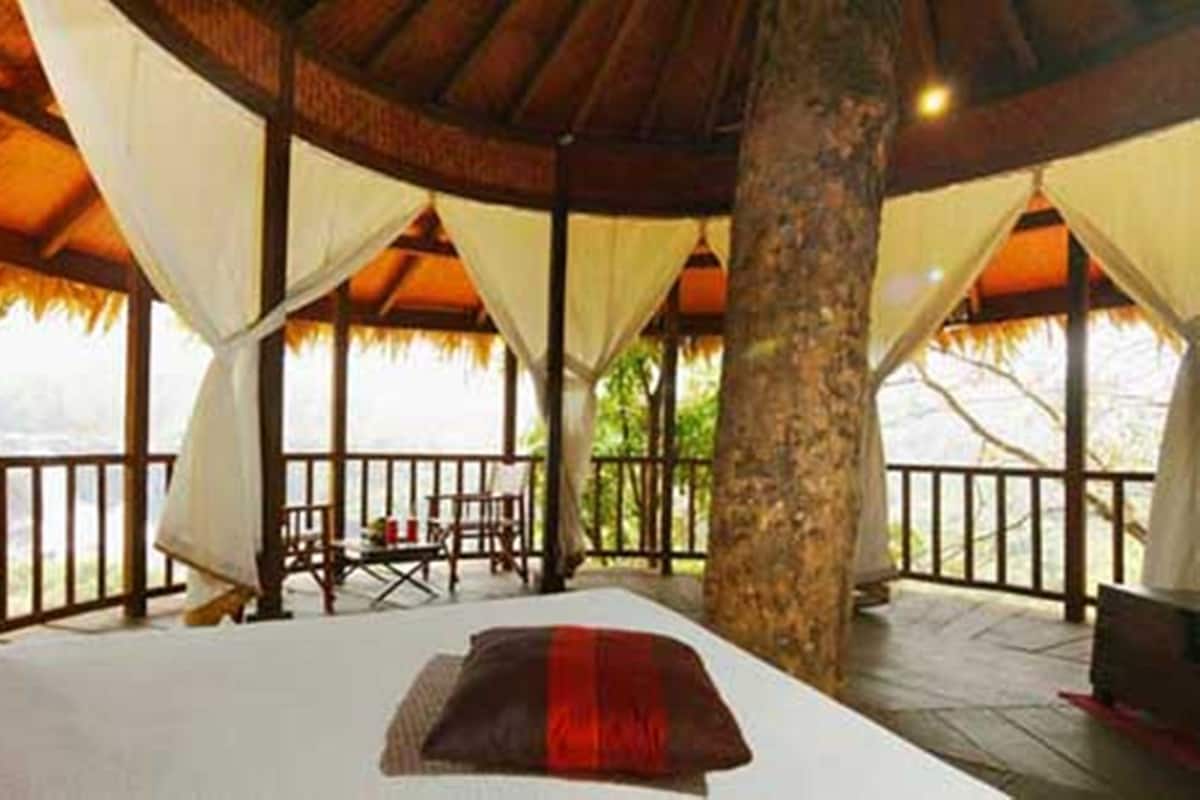 A room with a bed, a table, and chairs, and a view of the outdoors.