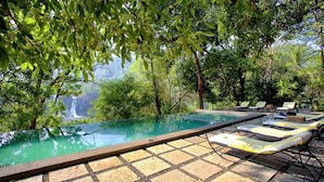 An infinity pool with lounge chairs and a waterfall view. - Rainforest Boutique Resort (Chalakudy)