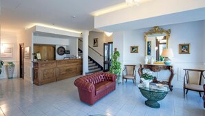 A spacious lobby with a red leather sofa, a wooden reception desk, and a large mirror.
