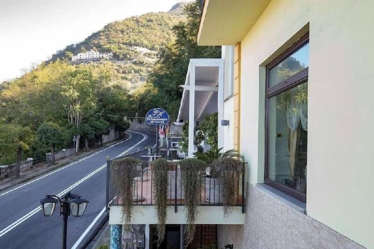 Un hôtel doté d’un balcon, une route en arrière-plan et un panneau indiquant un endroit situé à proximité.