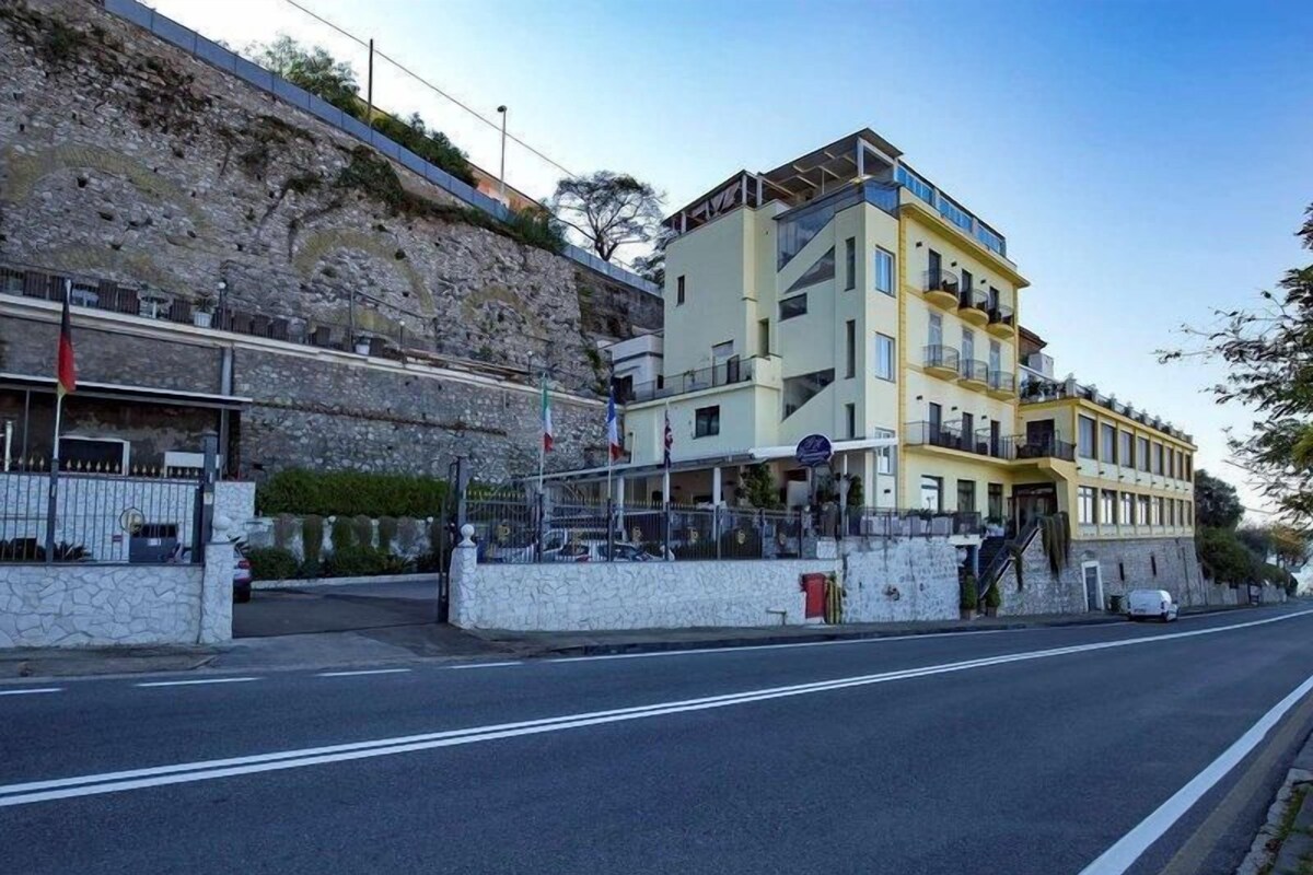 Un hôtel à plusieurs étages doté de balcons, d’un mur de soutènement en pierre et surplombant un ciel dégagé.