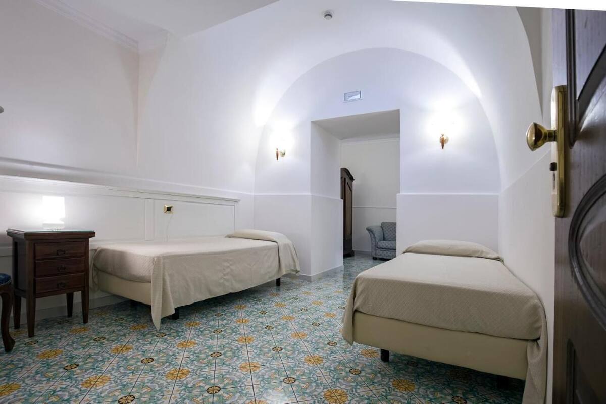 Une chambre avec deux lits, une petite commode en bois et une chaise.