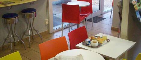 A dining area with tables and chairs, newspapers, and breakfast items.