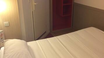 Una habitación de hotel con cama, televisión montada en la pared y armario.