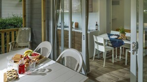 Een eetruimte met een tafel gedekt voor twee personen, met een fruitmand, gebak en een fles wijn.