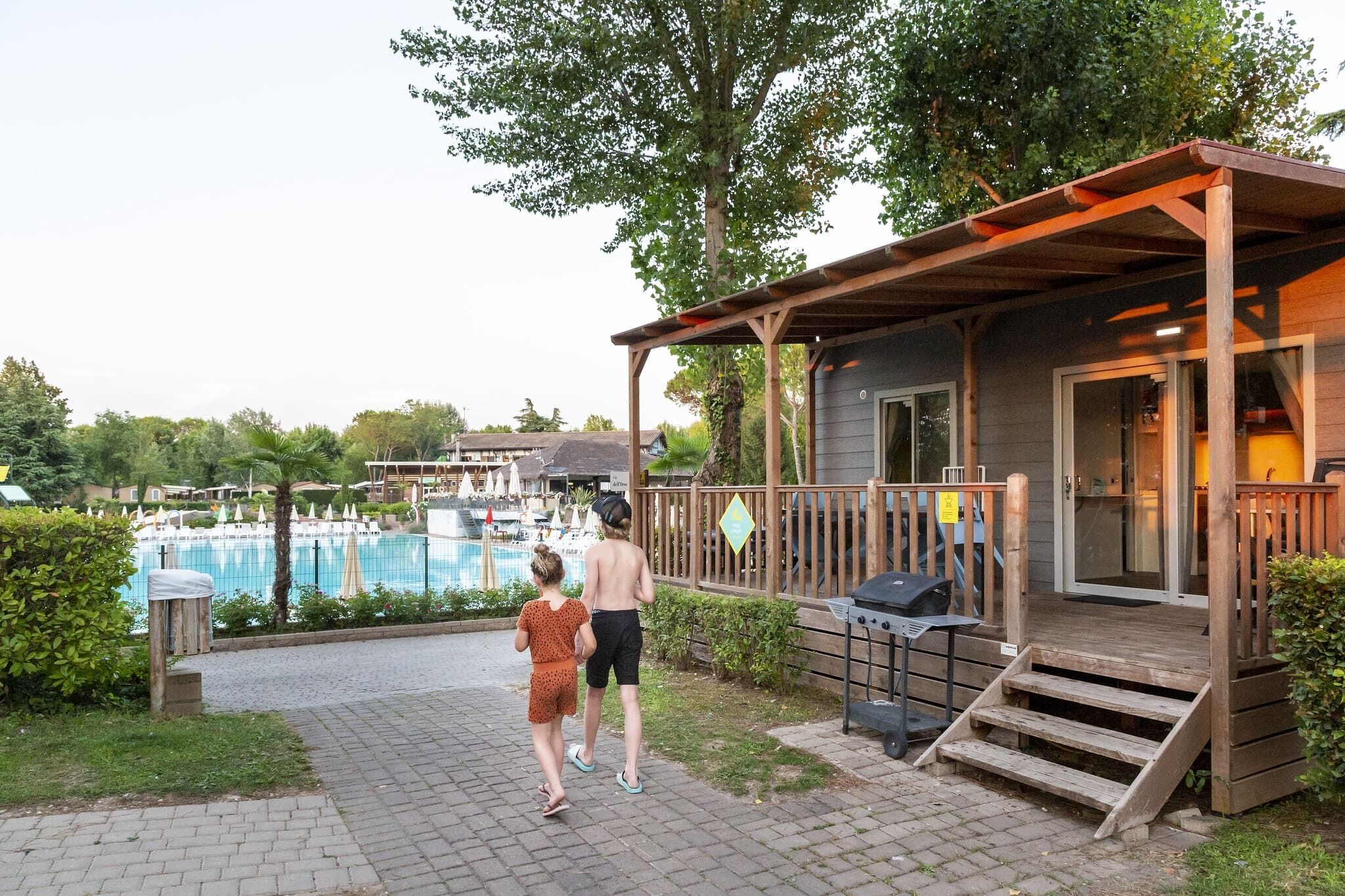 A wooden deck with a pool in the background.