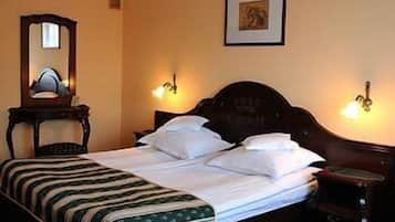 Una cama bien hecha con una colcha a rayas, una mesita de noche de madera con una lámpara, y un cuadro en la pared.