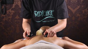 A person receiving a massage in a room with patterned wallpaper and a phone on the wall. - Hotel Chopin (Sochaczew)