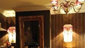 A room with a wooden floor, a fireplace, a mirror, a piano, and a chandelier. - Hotel Chopin (Sochaczew)