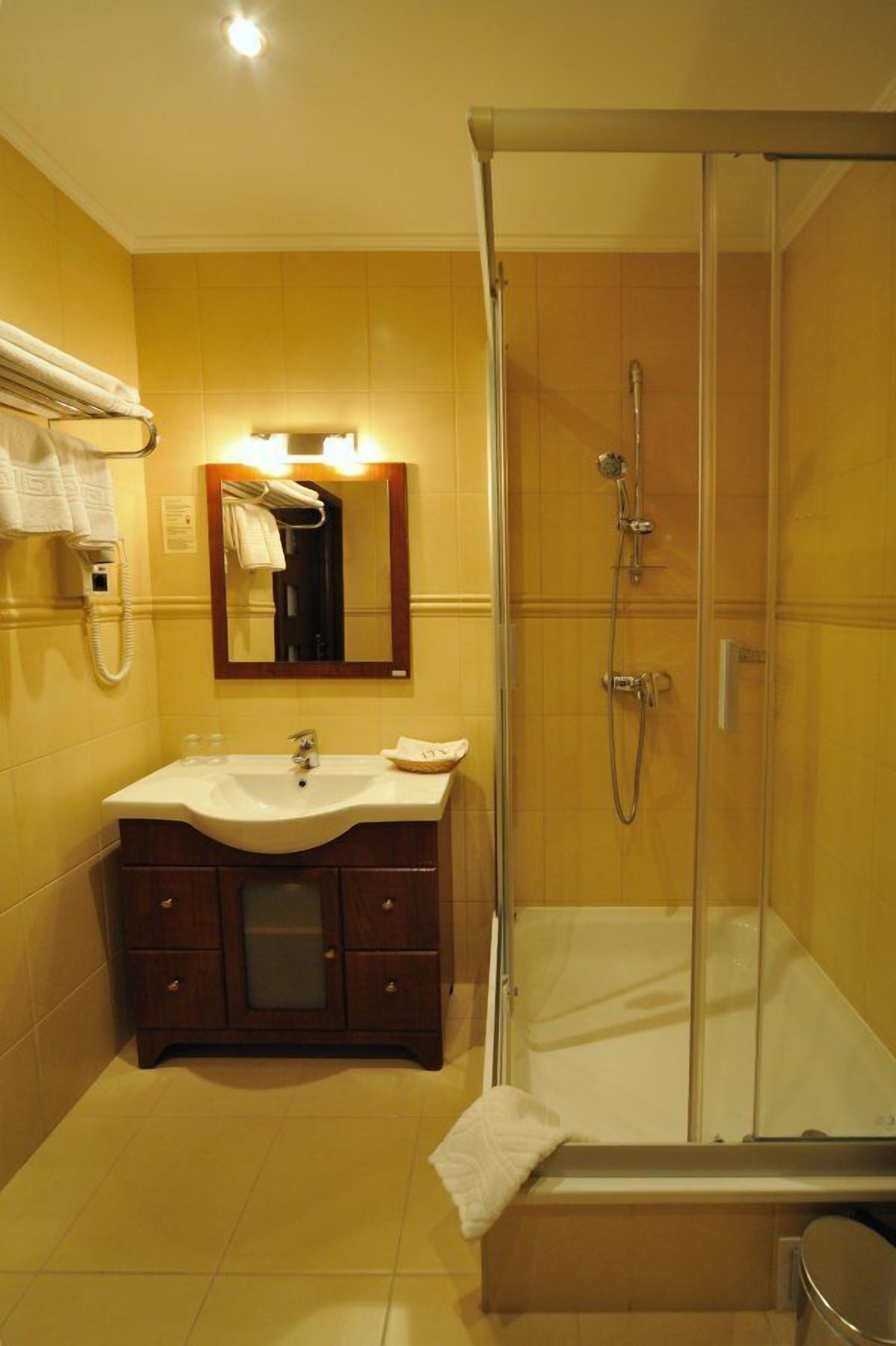 Baño con lavamanos, espejo y ducha.