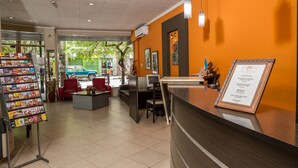 A reception area with a counter, seating, and a display of brochures. - Hotel Gran Vendimia by Bouquet (Mendoza)