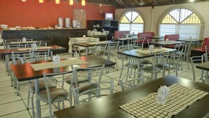 A restaurant with multiple tables and chairs, a counter with a television, and arched windows. - Hotel Gran Vendimia by Bouquet (Mendoza)