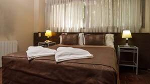 A hotel room with a large bed, two bedside lamps, a telephone, and a window with sheer curtains. - Hotel Gran Vendimia by Bouquet (Mendoza)